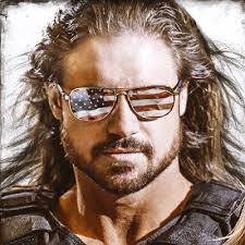 John Hennigan on being bald after losing a hair vs. hair match, how many pro wrestling names he’s had, a wild WWE Elimination Chamber spot